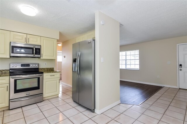 7338 Coventry Dr, Port Richey, FL 34668 - kitchen featuring stainless steel appliances, light tile patterned floors, a textured ceiling, cream cabinets, and baseboards