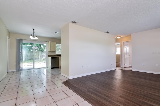 7338 Coventry Dr, Port Richey, FL 34668 - unfurnished living room with a chandelier, baseboards, a textured ceiling, and light wood-type flooring