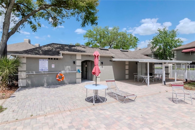 14053 Notreville Way, Tampa, FL 33624 - rear view of house featuring roof with shingles, stucco siding, fence, and a patio area