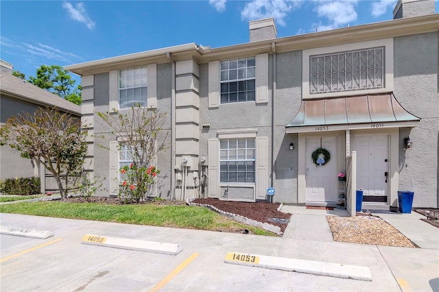 14053 Notreville Way, Tampa, FL 33624 - view of front of home with stucco siding, a chimney, and uncovered parking