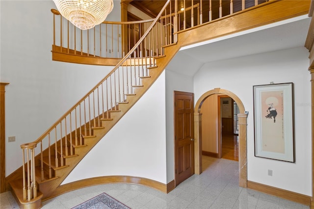staircase featuring a high ceiling, baseboards, arched walkways, and granite finish floor