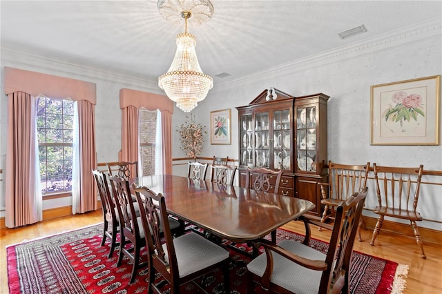 dining space featuring visible vents, wood finished floors, ornamental molding, and a notable chandelier
