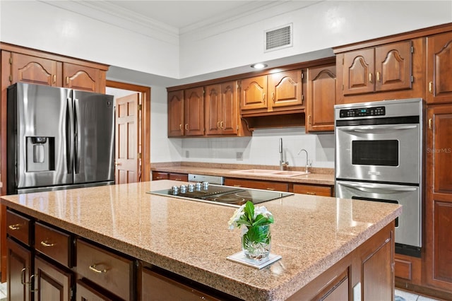 kitchen featuring a sink, stainless steel appliances, crown molding, visible vents, and a kitchen island