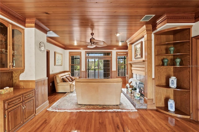 living area with wooden ceiling, light wood-type flooring, a fireplace, and wainscoting