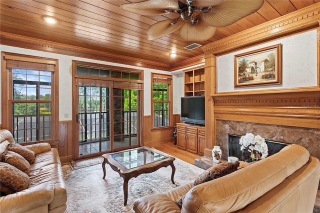 living room with light wood finished floors, a wainscoted wall, crown molding, visible vents, and wooden ceiling