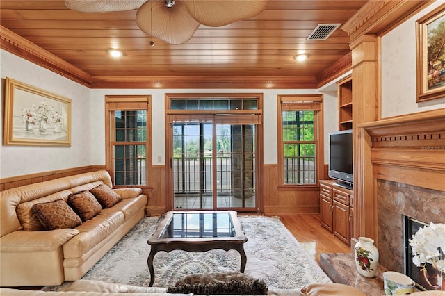 living room with a wainscoted wall, light wood-type flooring, wood ceiling, and crown molding