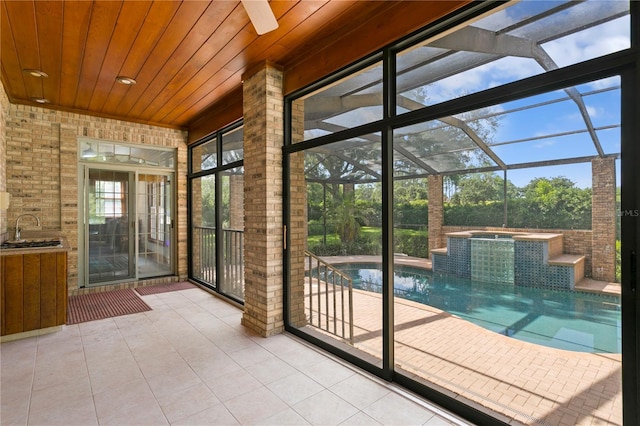 interior space featuring a sunroom, wood ceiling, tile patterned flooring, and brick wall