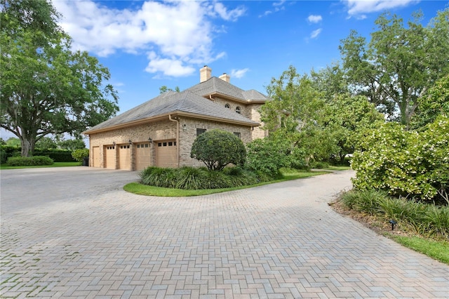 view of property exterior with a chimney, brick siding, and decorative driveway