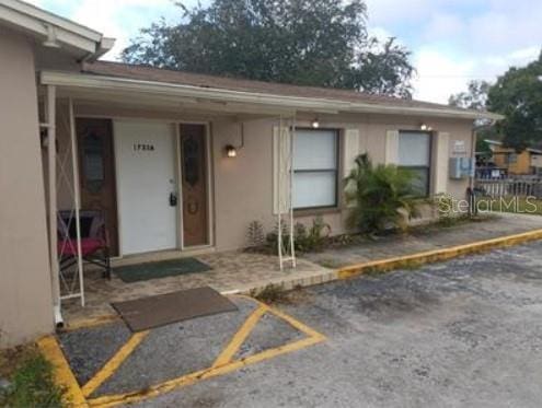 1733 Grand Blvd, Holiday, FL 34690 - view of exterior entry with stucco siding, uncovered parking, and fence