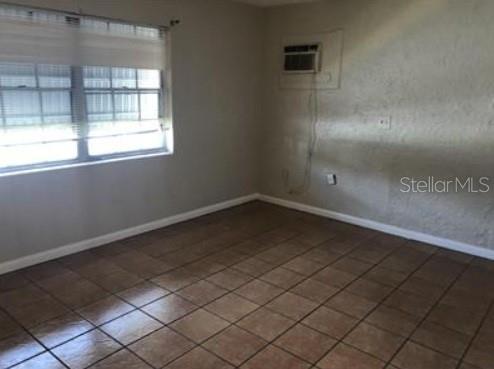 1733 Grand Blvd, Holiday, FL 34690 - tiled spare room featuring baseboards and a wall mounted AC