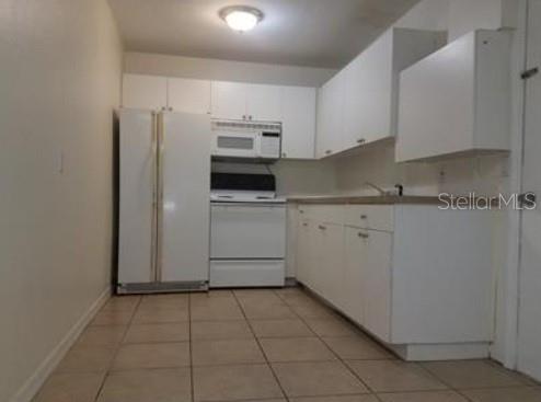 1733 Grand Blvd, Holiday, FL 34690 - kitchen featuring white appliances, white cabinetry, baseboards, and light tile patterned flooring