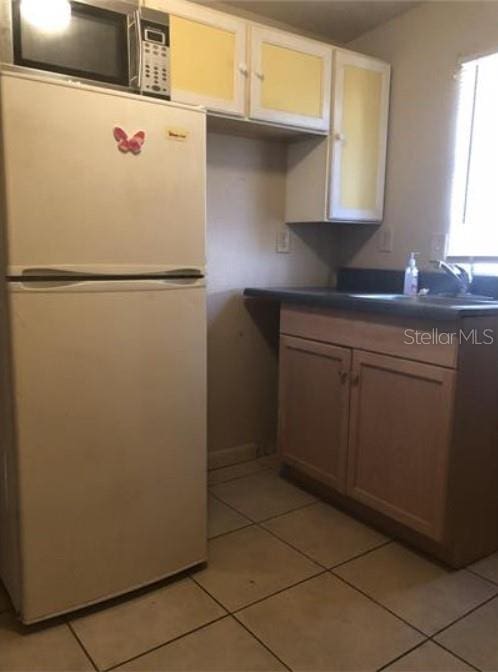 1733 Grand Blvd, Holiday, FL 34690 - kitchen with white appliances, a sink, light tile patterned floors, and dark countertops
