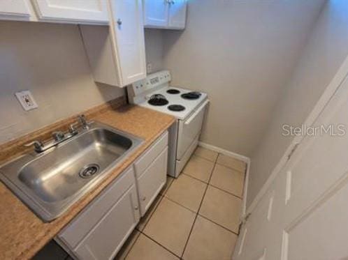1733 Grand Blvd, Holiday, FL 34690 - kitchen featuring light tile patterned floors, light countertops, white cabinets, white electric range oven, and a sink