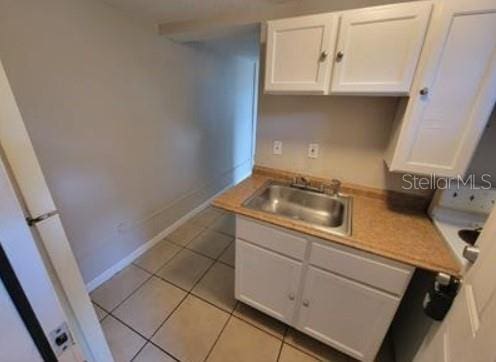 1733 Grand Blvd, Holiday, FL 34690 - kitchen with a sink, baseboards, white cabinetry, and light tile patterned flooring