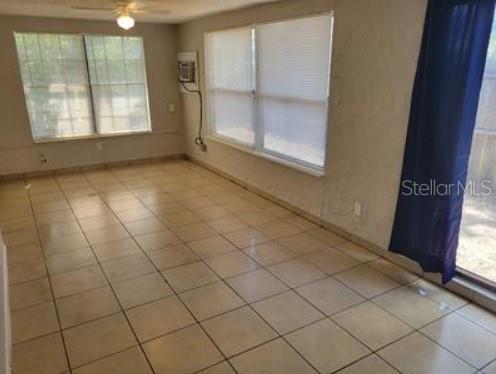 1733 Grand Blvd, Holiday, FL 34690 - tiled spare room featuring a wall mounted AC, ceiling fan, and plenty of natural light