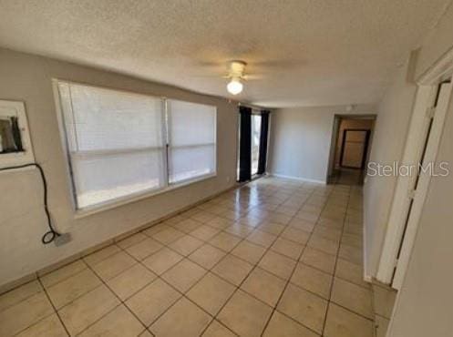 1733 Grand Blvd, Holiday, FL 34690 - spare room featuring a textured ceiling, light tile patterned flooring, baseboards, and a ceiling fan
