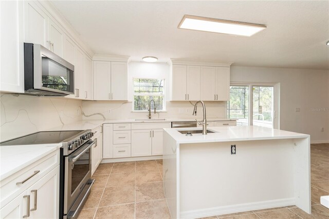 14319 Morristown Ave, Port Charlotte, FL 33981 - kitchen with stainless steel appliances, a sink, a kitchen island with sink, and white cabinetry