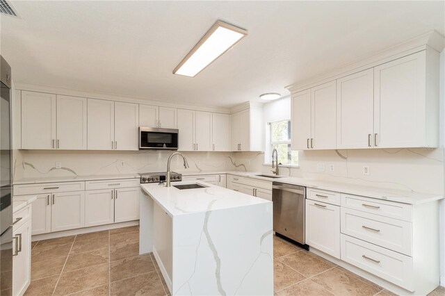 14319 Morristown Ave, Port Charlotte, FL 33981 - kitchen featuring appliances with stainless steel finishes, a sink, an island with sink, light stone countertops, and white cabinets