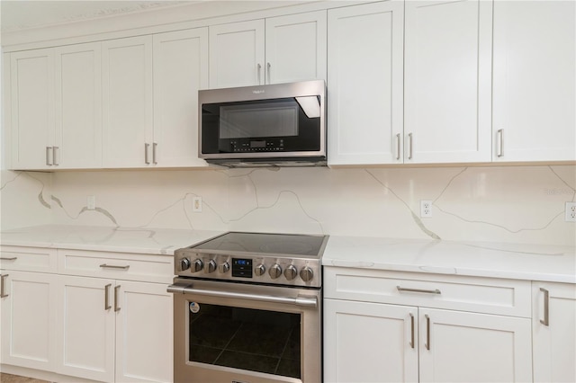 14319 Morristown Ave, Port Charlotte, FL 33981 - kitchen featuring appliances with stainless steel finishes, backsplash, white cabinetry, and light stone counters