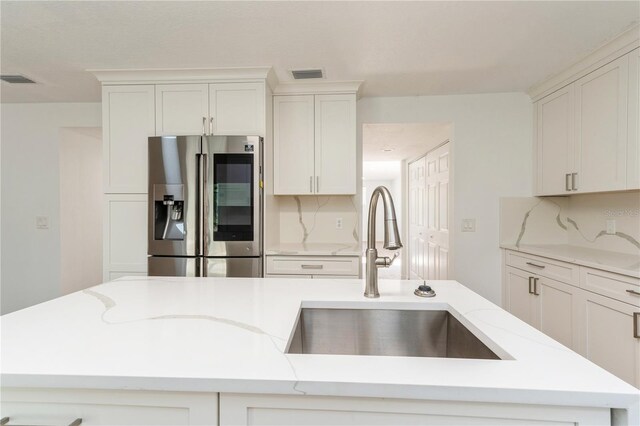 14319 Morristown Ave, Port Charlotte, FL 33981 - kitchen with stainless steel fridge with ice dispenser, a sink, light stone countertops, white cabinetry, and tasteful backsplash