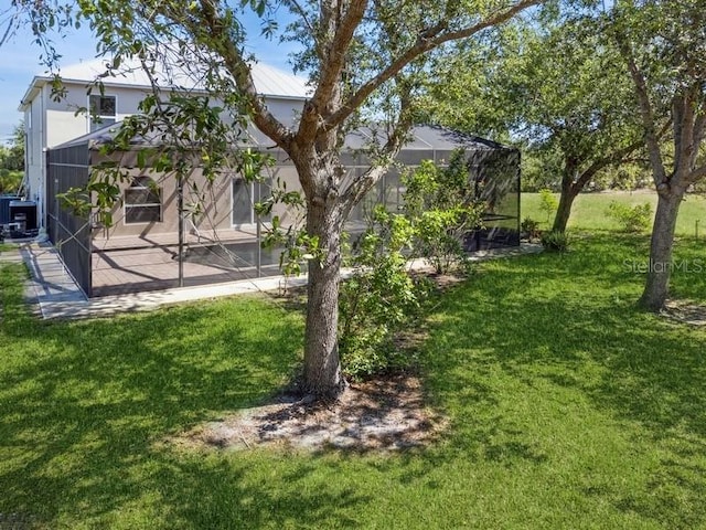 14319 Morristown Ave, Port Charlotte, FL 33981 - view of grassy yard featuring central AC unit, a patio, and glass enclosure