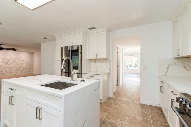 14319 Morristown Ave, Port Charlotte, FL 33981 - kitchen with stainless steel appliances, a sink, white cabinetry, and an island with sink
