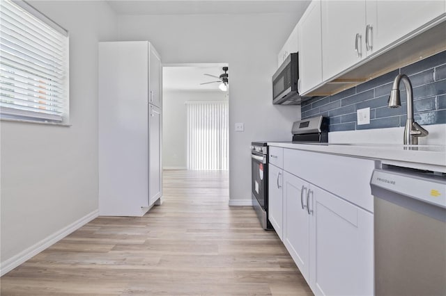 7139 Adare Dr, New Port Richey, FL 34653 - kitchen with white cabinetry, tasteful backsplash, stainless steel appliances, a sink, and light wood-style flooring