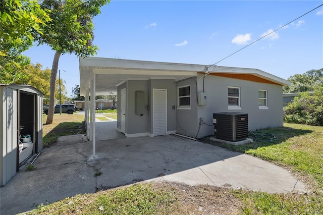 7139 Adare Dr, New Port Richey, FL 34653 - rear view of house featuring an outbuilding, a carport, central AC, a yard, and a storage shed