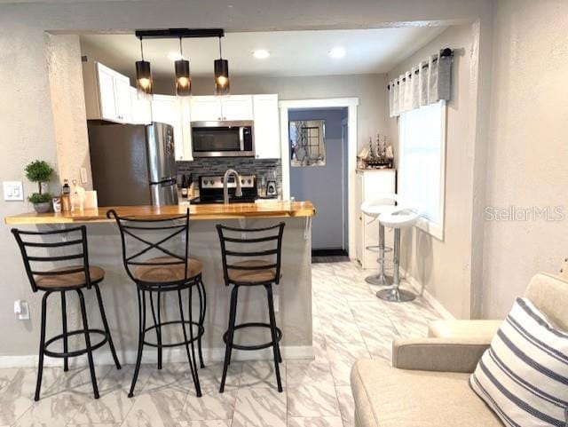 1408 San Juan Ct, Clearwater, FL 33756 - kitchen featuring appliances with stainless steel finishes, light marble finish floors, a kitchen breakfast bar, and backsplash
