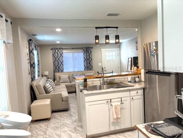 1408 San Juan Ct, Clearwater, FL 33756 - kitchen with freestanding refrigerator, open floor plan, a peninsula, light marble finish floors, and white cabinets