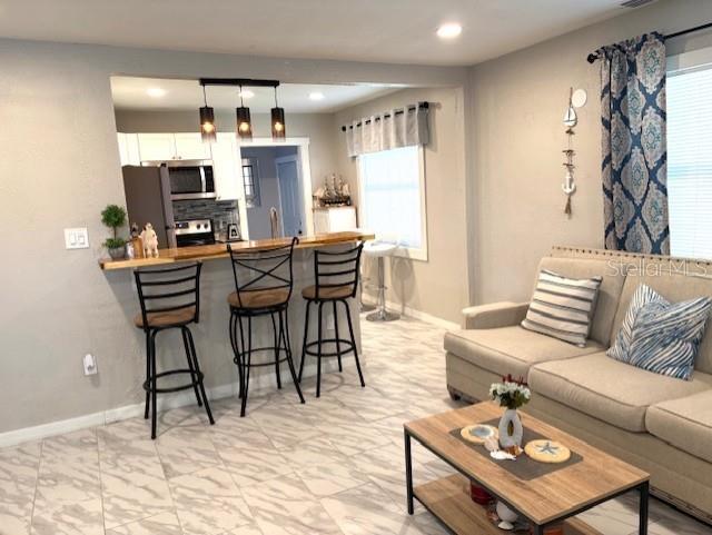 1408 San Juan Ct, Clearwater, FL 33756 - living room featuring baseboards, recessed lighting, and light marble finish floors