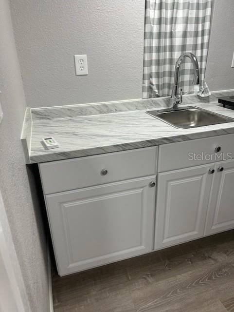 1408 San Juan Ct, Clearwater, FL 33756 - kitchen with a sink, a textured wall, white cabinets, dark wood-type flooring, and light countertops