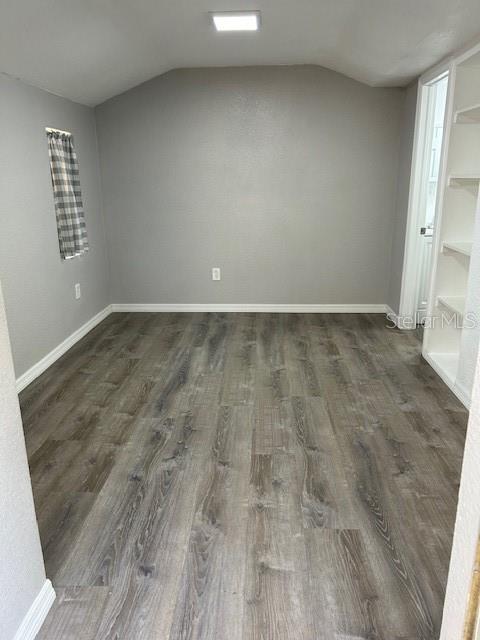 1408 San Juan Ct, Clearwater, FL 33756 - unfurnished room featuring dark wood-style floors, lofted ceiling, and baseboards