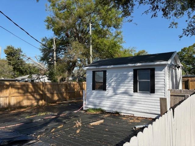 1408 San Juan Ct, Clearwater, FL 33756 - view of side of property with a fenced backyard, a deck, and an outdoor structure
