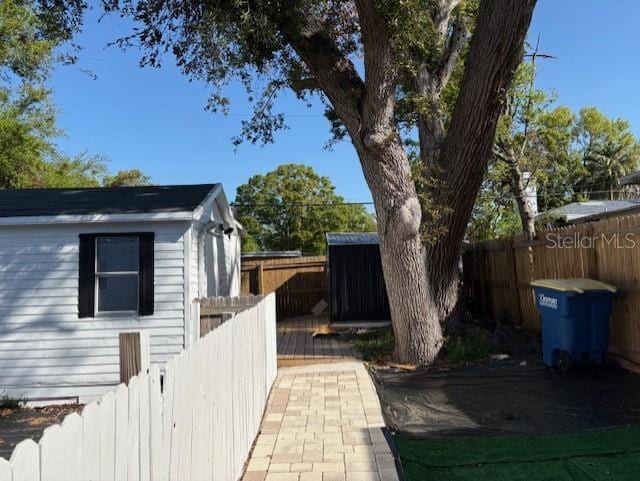 1408 San Juan Ct, Clearwater, FL 33756 - view of home's exterior with a storage unit, a fenced backyard, and an outdoor structure