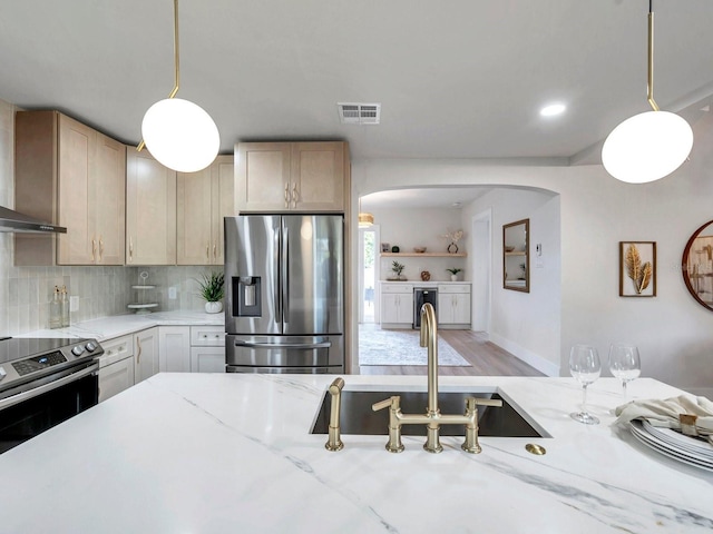 kitchen featuring visible vents, appliances with stainless steel finishes, arched walkways, light stone counters, and backsplash