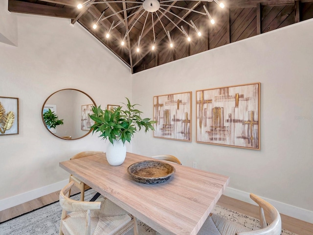 dining space featuring baseboards, high vaulted ceiling, wood finished floors, and rail lighting