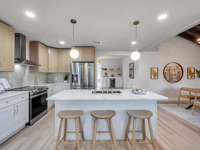 kitchen with light wood-type flooring, visible vents, appliances with stainless steel finishes, and wall chimney exhaust hood