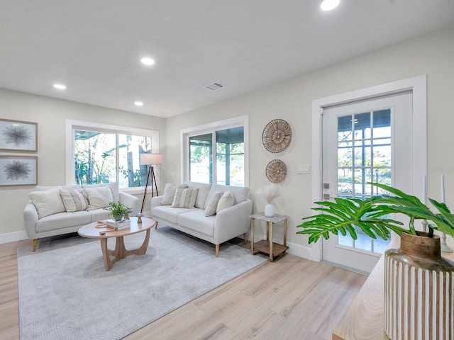 living area featuring baseboards, visible vents, light wood-style floors, and recessed lighting
