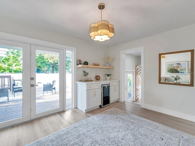 kitchen featuring light countertops, pendant lighting, light wood finished floors, and beverage cooler