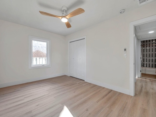 unfurnished bedroom featuring a closet, visible vents, baseboards, attic access, and light wood-type flooring