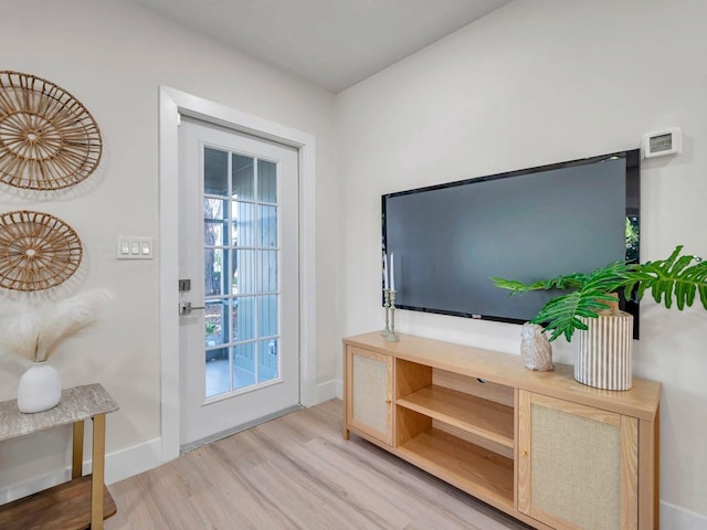 doorway to outside featuring baseboards and wood finished floors