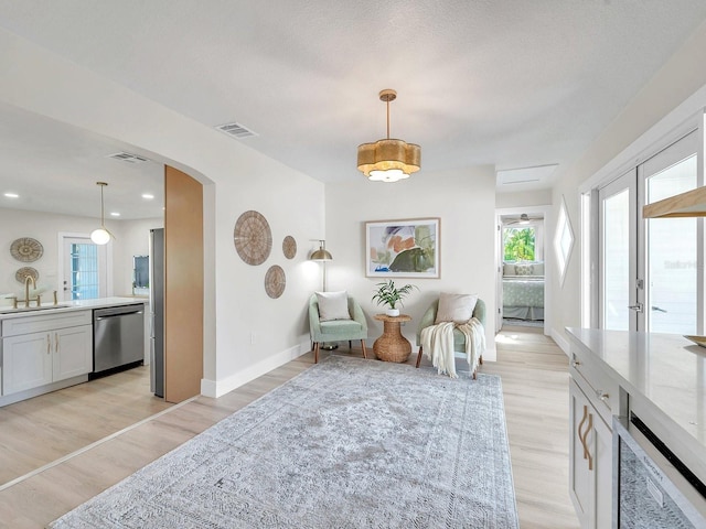 sitting room featuring arched walkways, baseboards, light wood-style floors, and visible vents