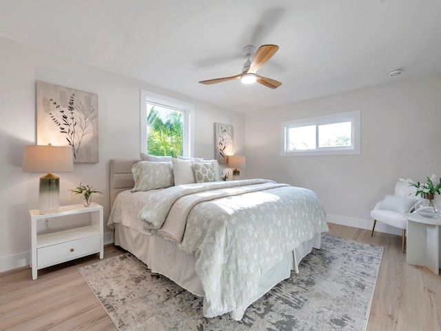 bedroom featuring baseboards, light wood-style floors, and ceiling fan