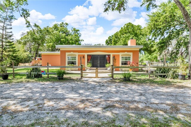 view of front of property with stucco siding, a chimney, covered porch, and a fenced front yard