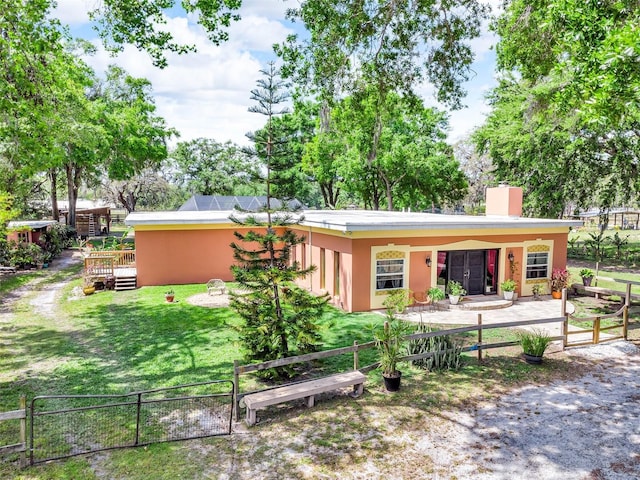 view of front of home featuring a chimney, a deck, fence, a front yard, and stucco siding
