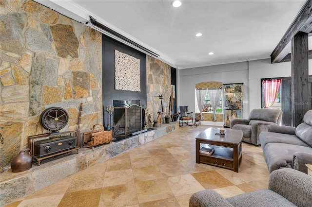 living area featuring recessed lighting, a stone fireplace, and crown molding
