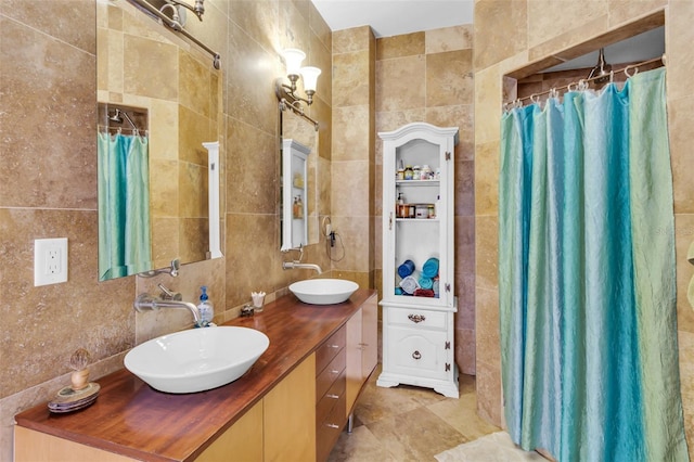 bathroom with tile walls, decorative backsplash, a sink, and double vanity