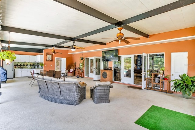 living area featuring beamed ceiling, light colored carpet, and ceiling fan