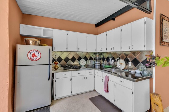 kitchen with white cabinets, freestanding refrigerator, and gas cooktop